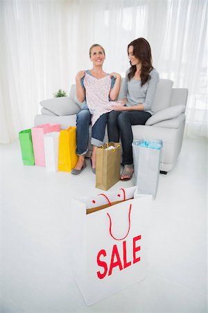 Women sitting on the sofa with purchase and shopping bag on foreground Stock Photo - Budget Royalty-Free & Subscription, Code: 400-06932865