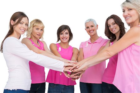 simsearch:400-06932887,k - Cheerful women posing in circle holding hands looking at camera  wearing pink for breast cancer on white background Fotografie stock - Microstock e Abbonamento, Codice: 400-06932878