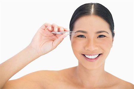 simsearch:614-03649482,k - Cheerful natural model using tweezers for her eyebrow on white background Photographie de stock - Aubaine LD & Abonnement, Code: 400-06933543