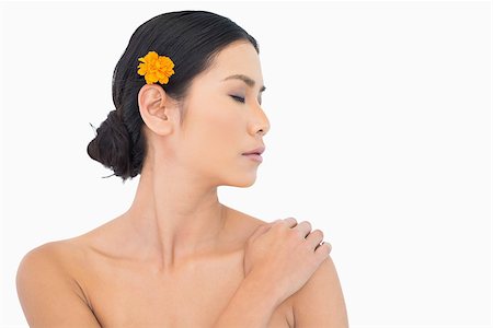 simsearch:6108-06905650,k - Pensive model with orange flower in hair touching her shoulder on white background Stock Photo - Budget Royalty-Free & Subscription, Code: 400-06933721