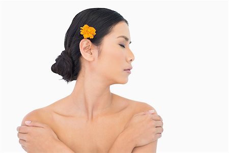 simsearch:6108-06905650,k - Pensive model with orange flower in hair touching her shoulders on white background Stock Photo - Budget Royalty-Free & Subscription, Code: 400-06933722