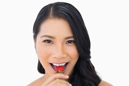 simsearch:693-06021794,k - Attractive brown haired model eating strawberry on white background Stock Photo - Budget Royalty-Free & Subscription, Code: 400-06933779