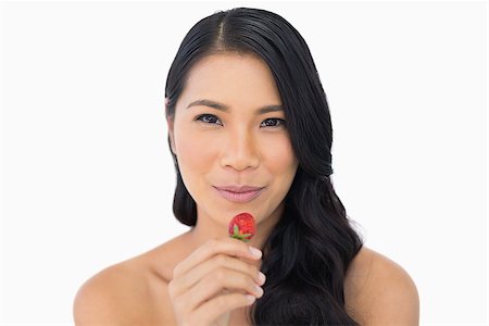 simsearch:693-06021794,k - Calm attractive brown haired model eating strawberry on white background Stock Photo - Budget Royalty-Free & Subscription, Code: 400-06933781