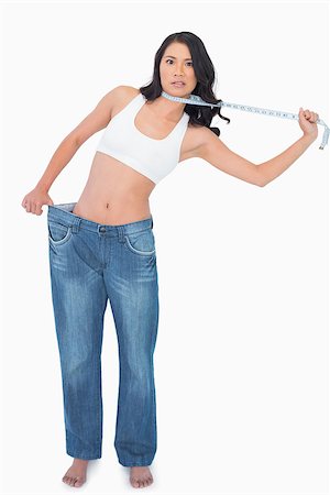 strangle women - Sexy woman wearing too big pants and strangling herself with measuring tape on white background Stock Photo - Budget Royalty-Free & Subscription, Code: 400-06933801