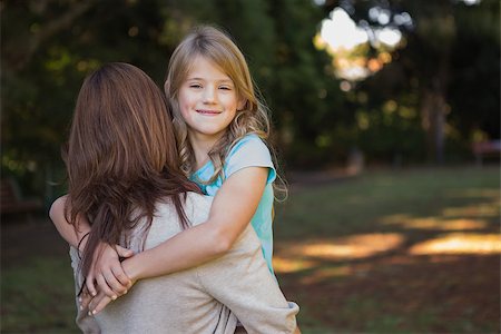 Child looking over her mothers shoulder in her arms smiling at camera Stock Photo - Budget Royalty-Free & Subscription, Code: 400-06933978