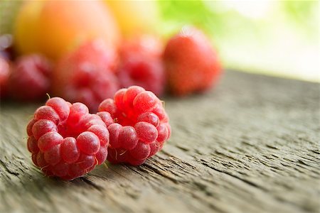simsearch:400-07667203,k - Ripe Sweet Raspberries on the Wooden Table Against the Heap of Summer Fruits and Berries Stock Photo - Budget Royalty-Free & Subscription, Code: 400-06948185