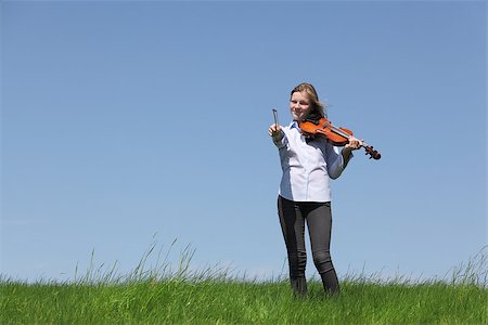 Teenage girl playing violin on meadow over blue sky Stock Photo - Budget Royalty-Free & Subscription, Code: 400-06948695
