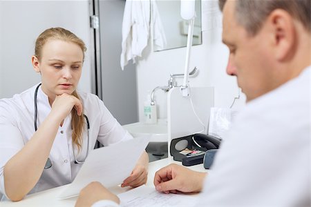 doctor speaking to young patient - Doctor and nurse discussing analyses sitting at the table Stock Photo - Budget Royalty-Free & Subscription, Code: 400-06949323