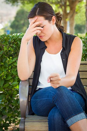 Upset Young Woman Sitting Alone on Bench Outside with Her Head in Her Hand and Clinched Fist. Stock Photo - Budget Royalty-Free & Subscription, Code: 400-06949714