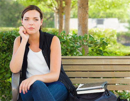 Melancholy Young Adult Woman Sitting on Bench Next to Books and Backpack. Stock Photo - Budget Royalty-Free & Subscription, Code: 400-06949710