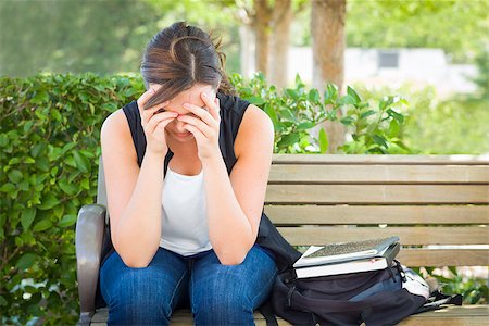 Upset Young Woman Sitting Alone with Her Head in Her Hands on Bench Next to Books and Backpack. Stock Photo - Budget Royalty-Free & Subscription, Code: 400-06949712