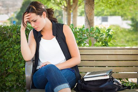 Upset Young Woman Sitting Alone with Her Head in Her Hands on Bench Next to Books and Backpack. Foto de stock - Super Valor sin royalties y Suscripción, Código: 400-06949713
