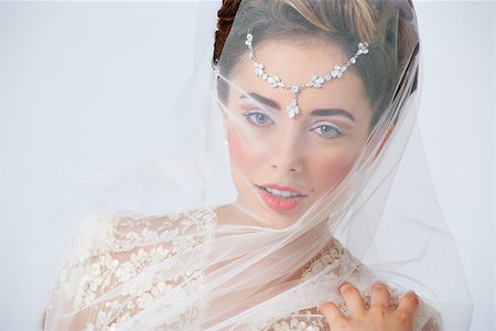 simsearch:400-04762831,k - Portrait of beautiful happy bride posing with veil covering her face. Studio shot. Stock Photo - Budget Royalty-Free & Subscription, Code: 400-06949728
