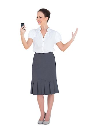 Smiling businesswoman looking at her phone while posing on white background Stock Photo - Budget Royalty-Free & Subscription, Code: 400-06955133