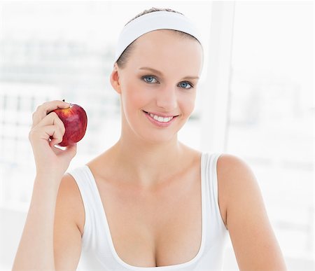 simsearch:685-02937448,k - Smiling pretty sportswoman holding an apple in a bright room Stock Photo - Budget Royalty-Free & Subscription, Code: 400-06955810