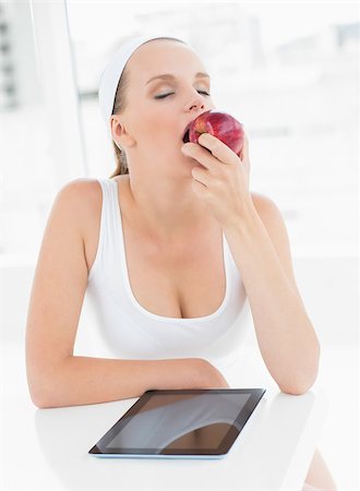 simsearch:685-02937448,k - Relaxed pretty sportswoman eating an apple in a bright room Stock Photo - Budget Royalty-Free & Subscription, Code: 400-06955820