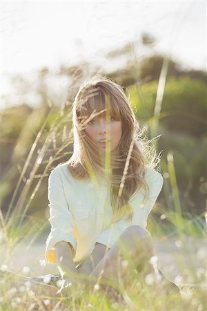 simsearch:400-06956665,k - Blonde hipster girl sitting on the grass looking at camera from behind blades in the sunlight Stockbilder - Microstock & Abonnement, Bildnummer: 400-06955928