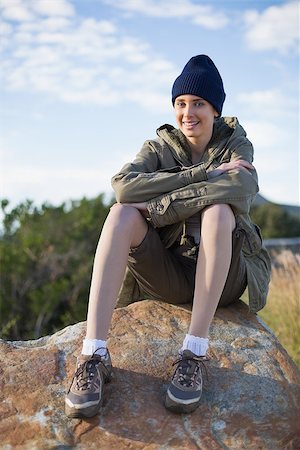 simsearch:400-06956627,k - Smiling woman wearing cap sitting on a rock looking at camera in the countryside Stock Photo - Budget Royalty-Free & Subscription, Code: 400-06956526