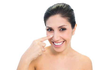 simsearch:400-06960125,k - Smiling brunette pointing to nose and looking at camera on white background Photographie de stock - Aubaine LD & Abonnement, Code: 400-06957956