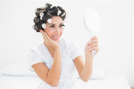 Pretty brunette in hair rollers looking in hand mirror at home in bedroom Stock Photo - Budget Royalty-Free & Subscription, Code: 400-06958203