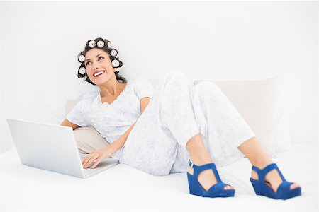 simsearch:693-06323945,k - Happy brunette in hair rollers and wedge shoes using her laptop on bed in bedroom at home Stock Photo - Budget Royalty-Free & Subscription, Code: 400-06958258