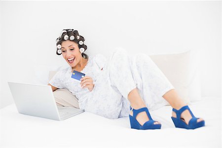 simsearch:693-06323945,k - Excited brunette in hair rollers and wedge shoes using her laptop for shopping online at home in bedroom Stock Photo - Budget Royalty-Free & Subscription, Code: 400-06958263