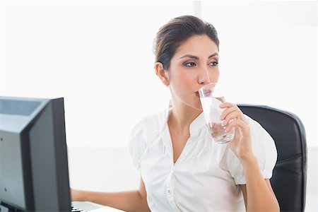Happy businesswoman drinking a glass of water at her desk in her workplace Stock Photo - Budget Royalty-Free & Subscription, Code: 400-06958615