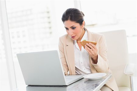 Focused businesswoman eating lunch as she is working at the office Stock Photo - Budget Royalty-Free & Subscription, Code: 400-06958791