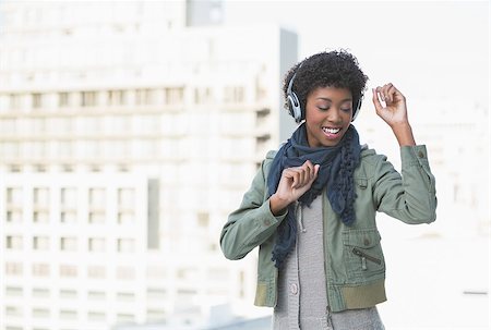 simsearch:400-08430017,k - Smiling casual model dancing while listening to music outdoors on a sunny day Stock Photo - Budget Royalty-Free & Subscription, Code: 400-06959430
