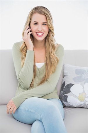 Happy pretty blonde on the phone sitting on cosy sofa in bright living room Stock Photo - Budget Royalty-Free & Subscription, Code: 400-06959720
