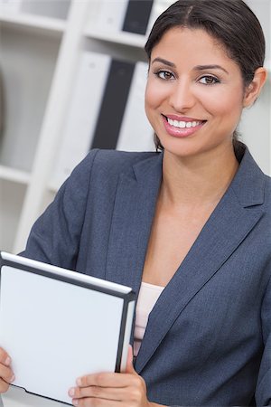 Beautiful young Latina Hispanic woman or businesswoman in smart business suit sitting at a desk in an office using a tablet computer Stock Photo - Budget Royalty-Free & Subscription, Code: 400-06950307