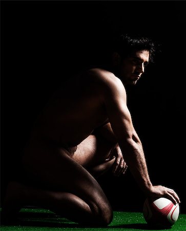 Side profile of naked young man kneeling full length with a rugby ball on isolated black background Stock Photo - Budget Royalty-Free & Subscription, Code: 400-06952723