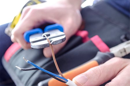 Closeup of worker's hands cutting electric wires with pliers. Stockbilder - Microstock & Abonnement, Bildnummer: 400-06953446