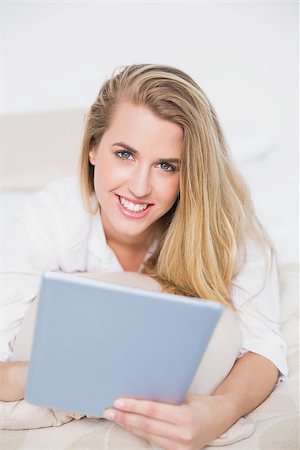 simsearch:693-07542343,k - Smiling model using her tablet lying on cosy bed in bright bedroom Stock Photo - Budget Royalty-Free & Subscription, Code: 400-06960018