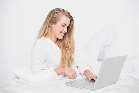 simsearch:693-07542343,k - Smiling pretty model using her laptop lying on cosy bed in bright bedroom Stock Photo - Budget Royalty-Free & Subscription, Code: 400-06960025