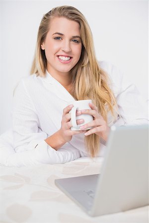 simsearch:693-07542343,k - Happy pretty model holding coffee lying on cosy bed in bright bedroom Stock Photo - Budget Royalty-Free & Subscription, Code: 400-06960028