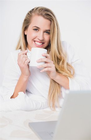 simsearch:693-07542343,k - Smiling pretty model holding coffee lying on cosy bed in bright bedroom Stock Photo - Budget Royalty-Free & Subscription, Code: 400-06960029