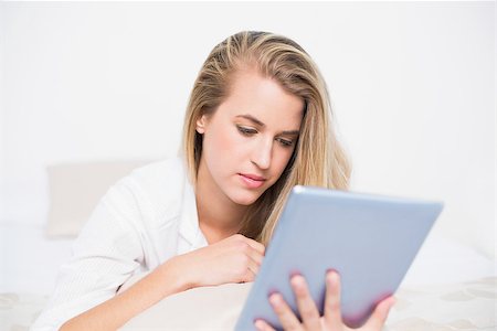 simsearch:693-07542343,k - Focused pretty model using her tablet pc lying on cosy bed in bright bedroom Stock Photo - Budget Royalty-Free & Subscription, Code: 400-06960023