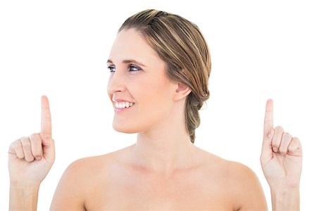 simsearch:400-06960125,k - Smiling woman pointing up looking away against white background Photographie de stock - Aubaine LD & Abonnement, Code: 400-06960061