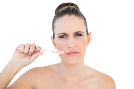 simsearch:400-06960125,k - Serious pretty woman brushing her teeth on white background Photographie de stock - Aubaine LD & Abonnement, Code: 400-06960106