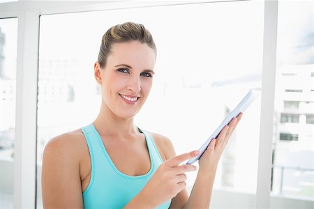 Cheerful woman in sportswear holding tablet looking at camera Stock Photo - Budget Royalty-Free & Subscription, Code: 400-06960301