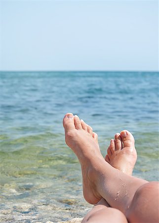 two female legs on beach over sea waves and blue sky Stockbilder - Microstock & Abonnement, Bildnummer: 400-07036243
