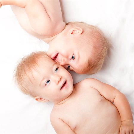 Two cute adorable twins faces showing special friendship connection while laying down, on white. Stock Photo - Budget Royalty-Free & Subscription, Code: 400-07038382