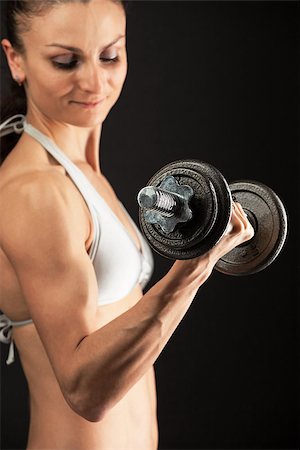 pic of girls with biceps - Muscular young woman lifting a dumbbell over black Stock Photo - Budget Royalty-Free & Subscription, Code: 400-07032916