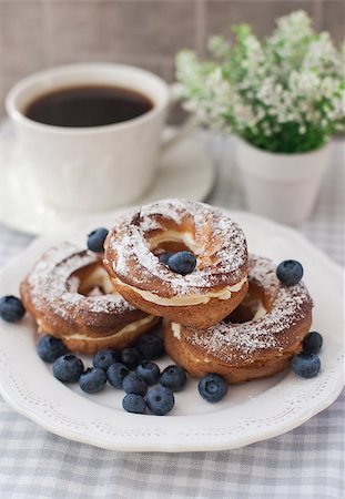 picture of plate of doughnuts - Three fresh ring cakes - cream puffs made of choux pastry, with blueberries and cup of coffe on the background. Photographie de stock - Aubaine LD & Abonnement, Code: 400-07047087