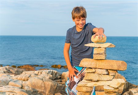 Boy building inukshuk on the rocky beach (Duncan Cove, Nova Scotia, Canada) Foto de stock - Super Valor sin royalties y Suscripción, Código: 400-07048305