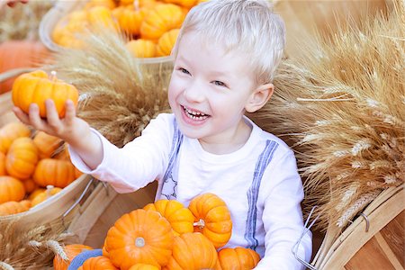 adorable smiling boy holding small pumpkin at the pumpkin patch Photographie de stock - Aubaine LD & Abonnement, Code: 400-07043373