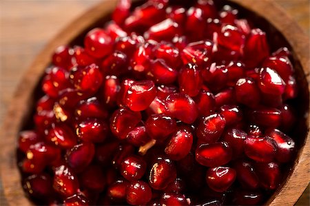 simsearch:640-02656973,k - Loose pomegranate (Punica granatum) seeds in a wood bowl shot on a wood table. Pomegranates are widely used in middle eastern and mediterranean culture. It is called a super food because of its many health benefits, such as being an antioxidant and having a high concentration of vitamin C. Fotografie stock - Microstock e Abbonamento, Codice: 400-07043703