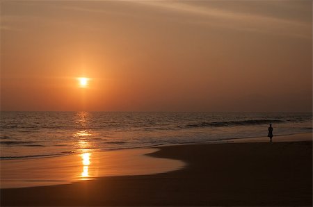 This is a sundown on the ocean coast. The  woman is walking along the seaside. Fotografie stock - Microstock e Abbonamento, Codice: 400-07054391