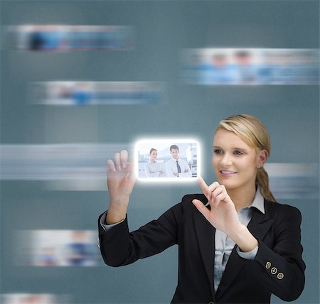 Blonde businesswoman touching digital interface showing coworkers Stock Photo - Budget Royalty-Free & Subscription, Code: 400-07057313